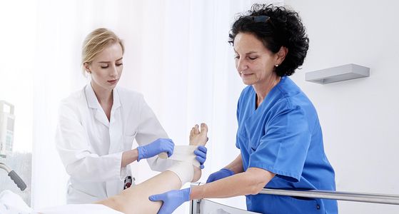 A doctor and a nurse bandage a patient's foot